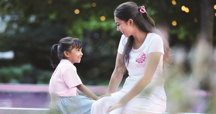 big girl little girl looking into each others eyes smiling in front of pink pool