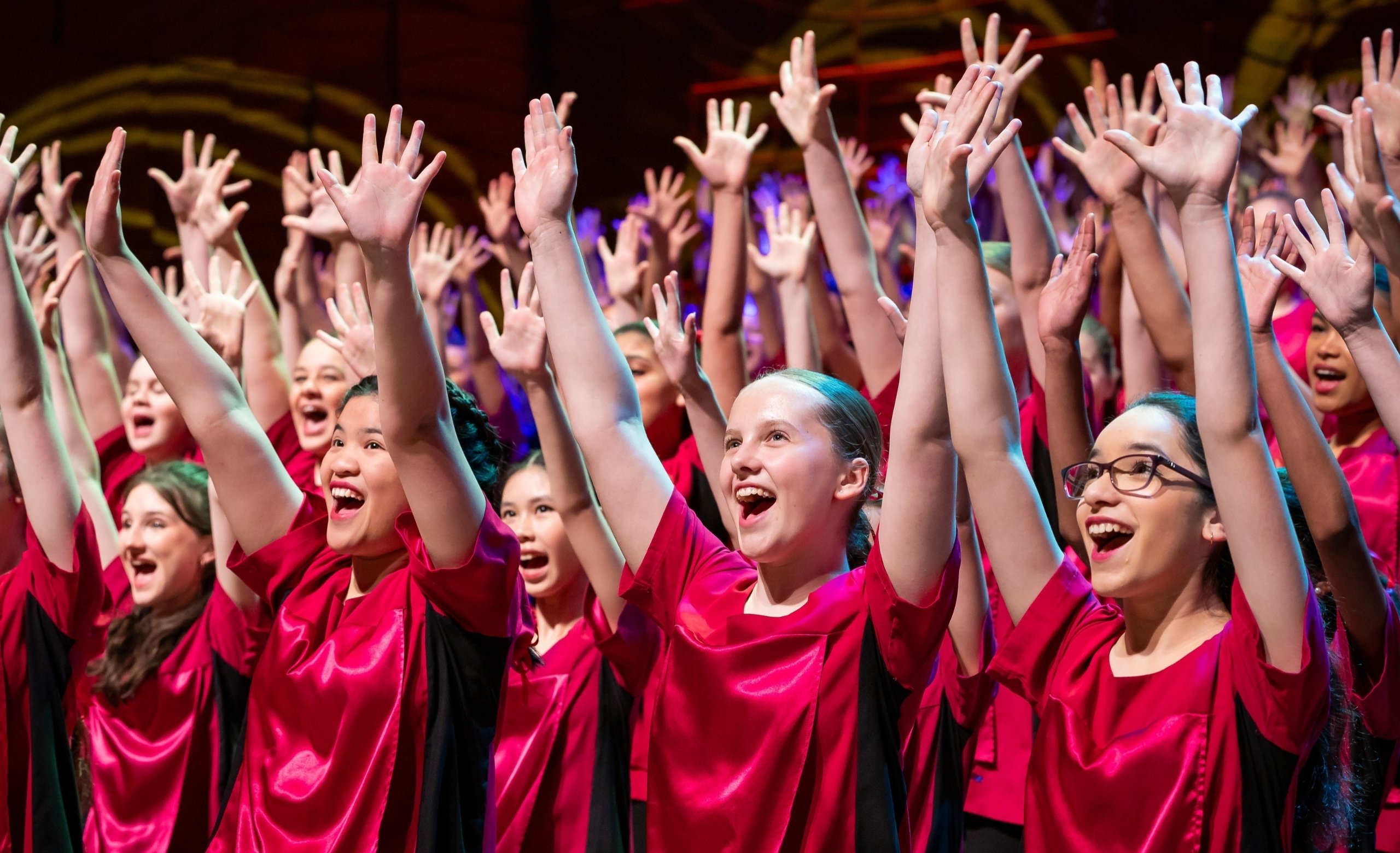 young women in red performance tops performing with arms up