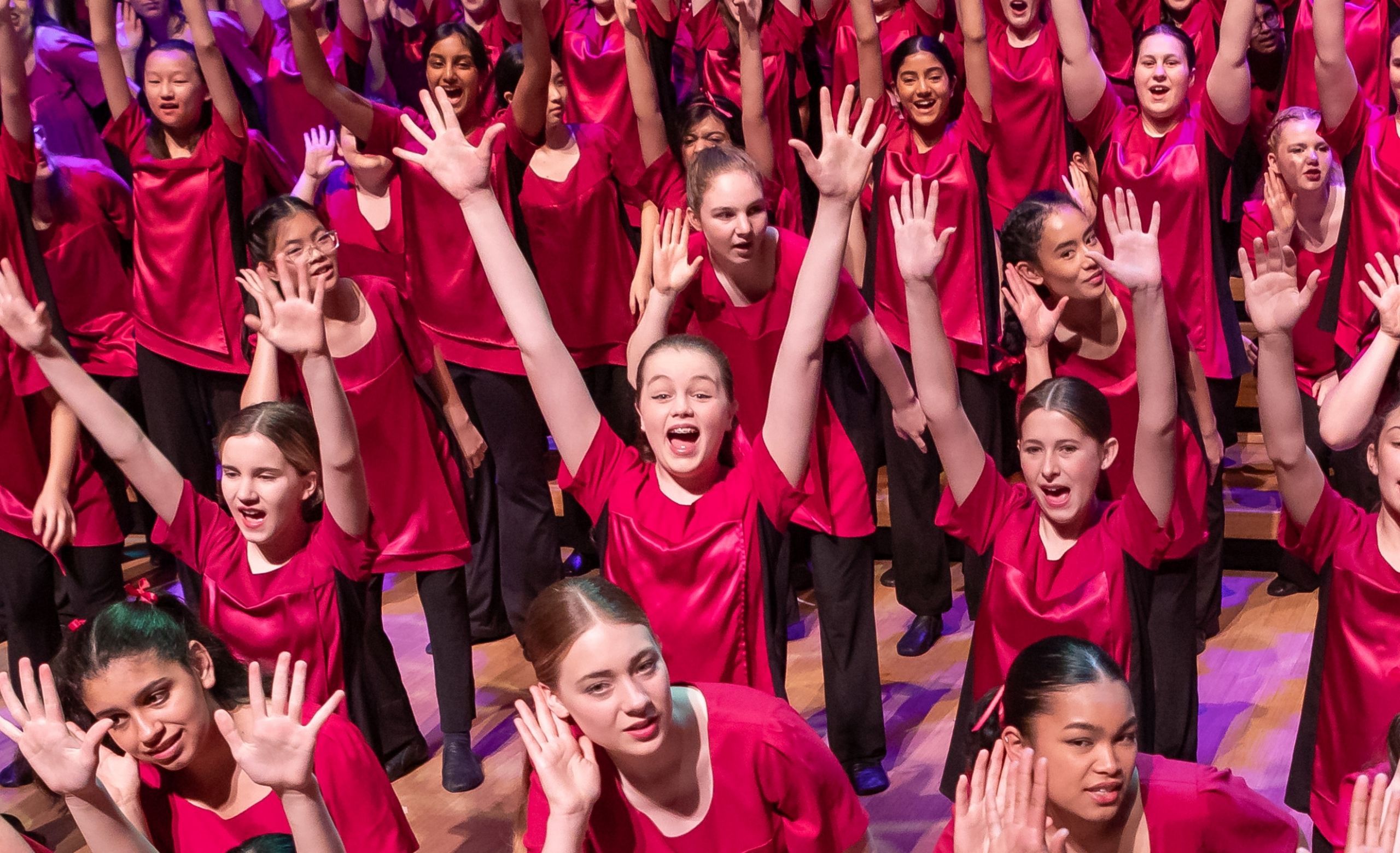 girls in silk red performance tops perfoming with their arms in the air