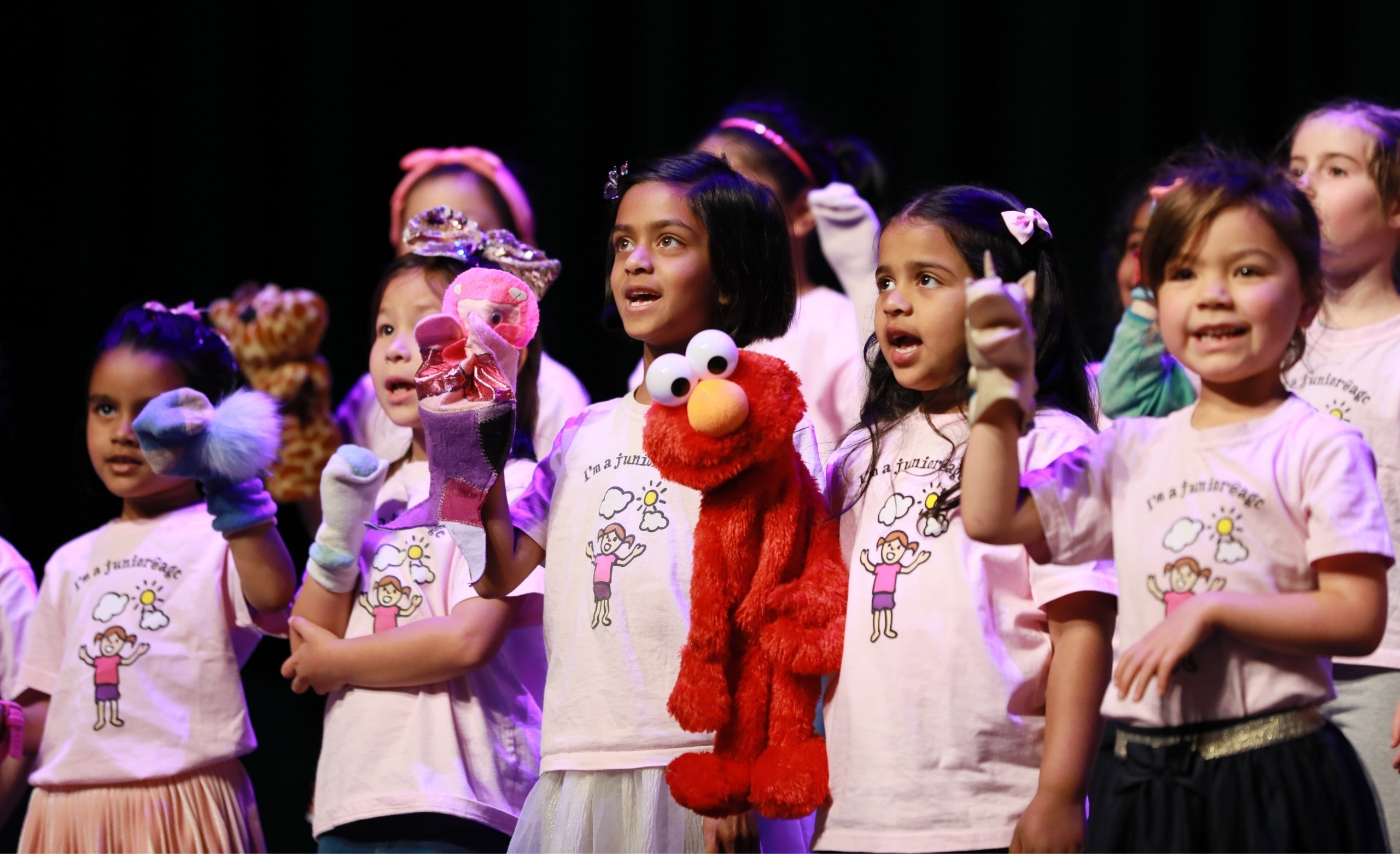 girls in pink shirts perfoming with puppets