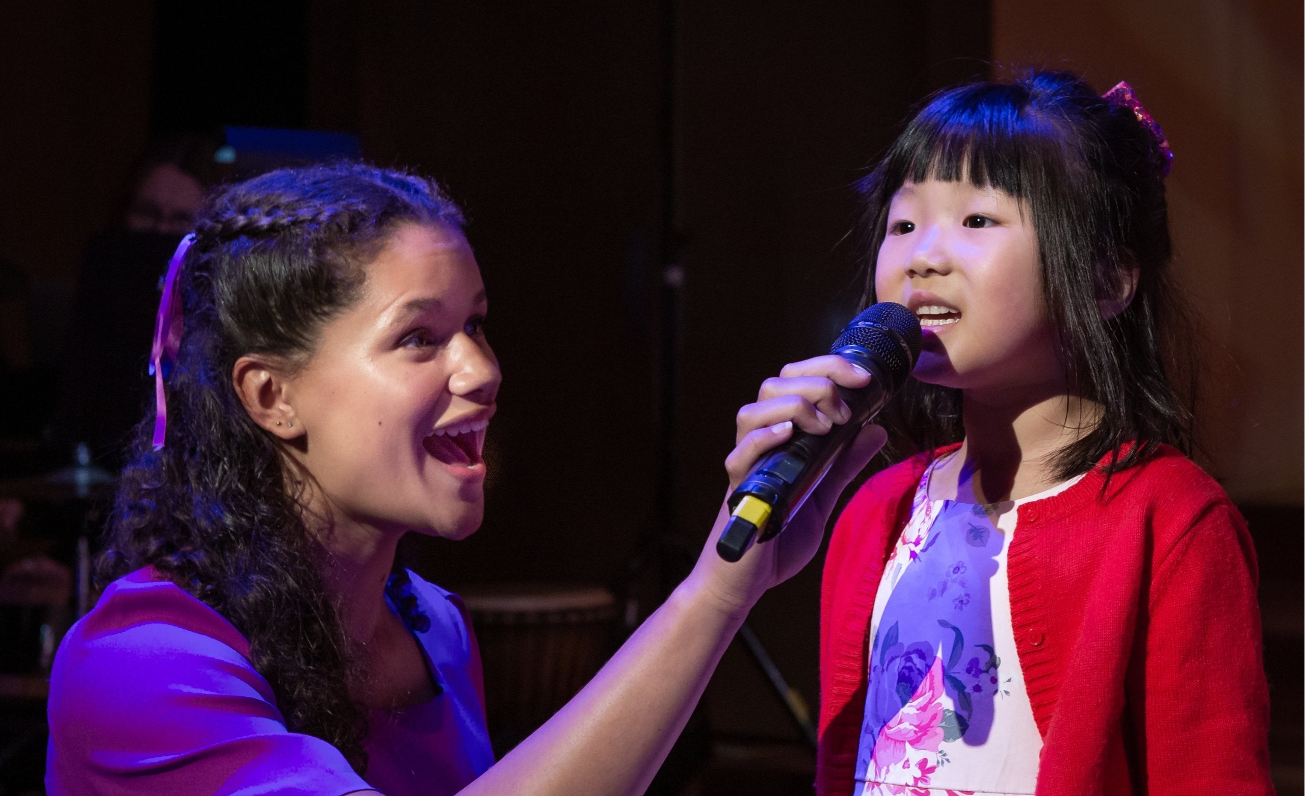 Older chorister guiding younger chorister in song.