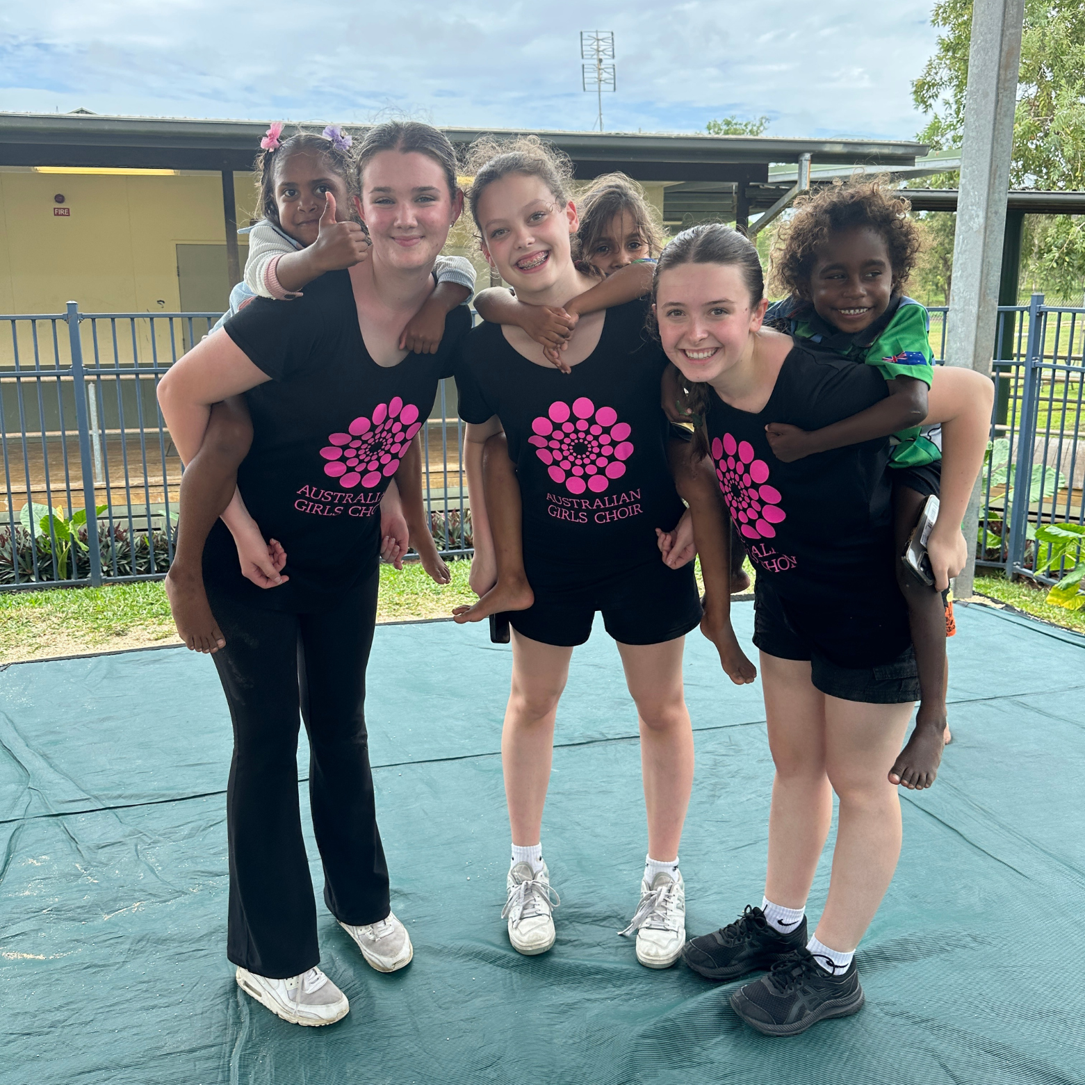 Three AGC girls stand piggybacking three Lockhart locals smiling