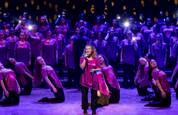 AGC choristers perform on stage in a group with beautiful purple lighting