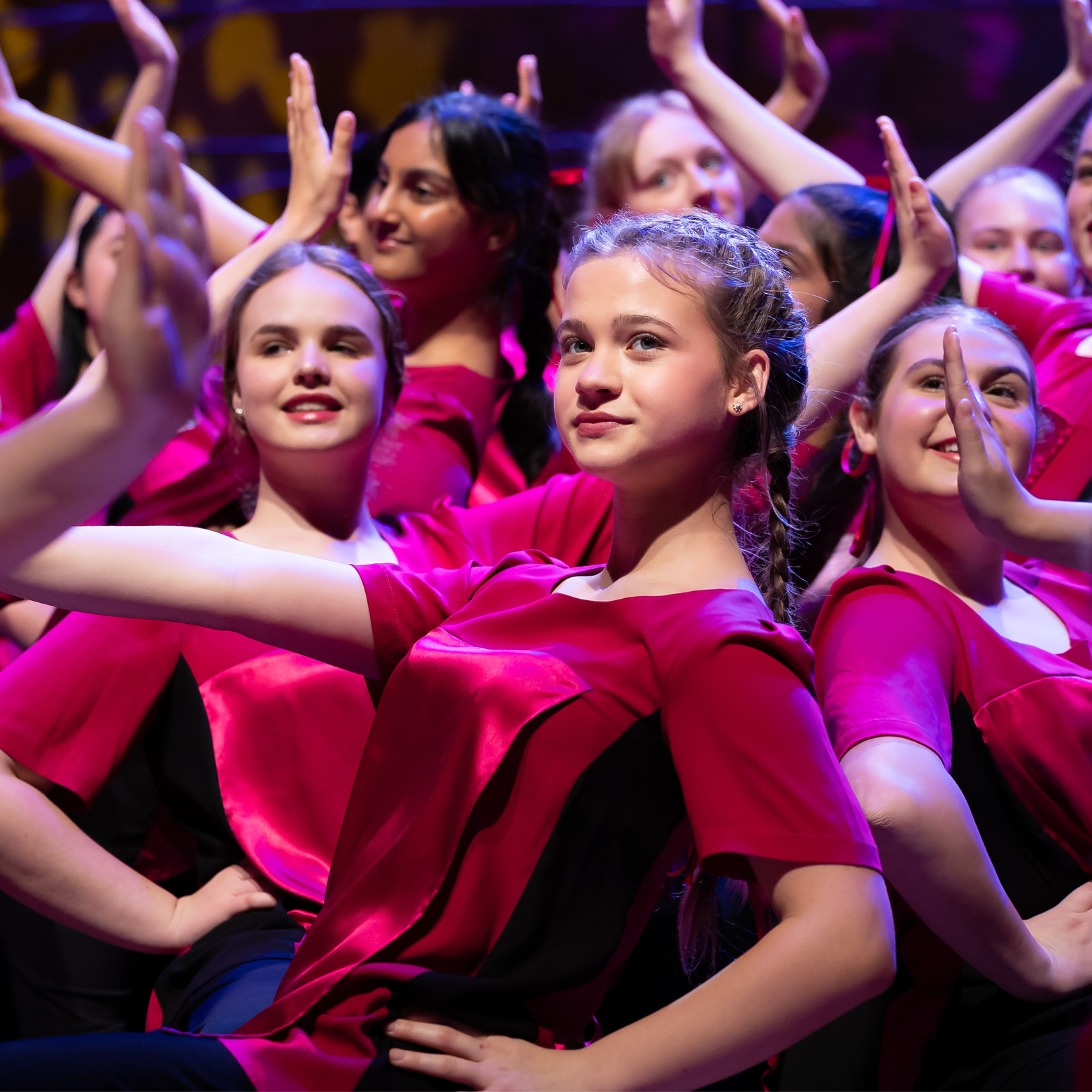 Camerata perform on stage during the AGCC in a big group number with their arms up