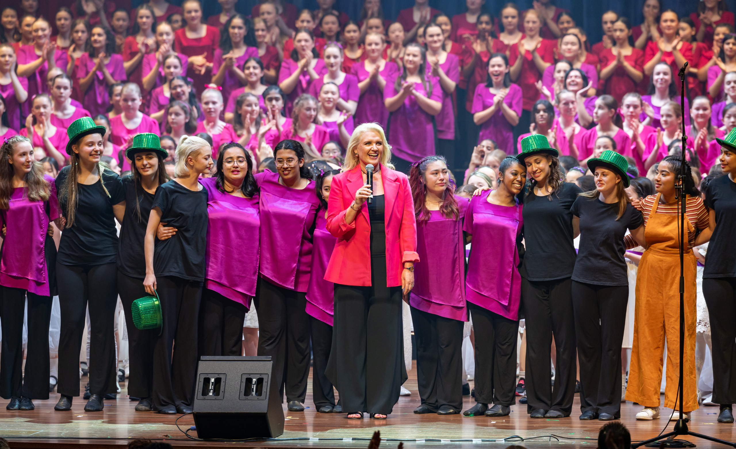 Nicole Muir AM speaks during an AGC Annual Concert surrounded by choristers.