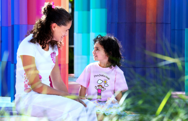 An AGC big girl and little girl laugh and smile together in a colourful setting.