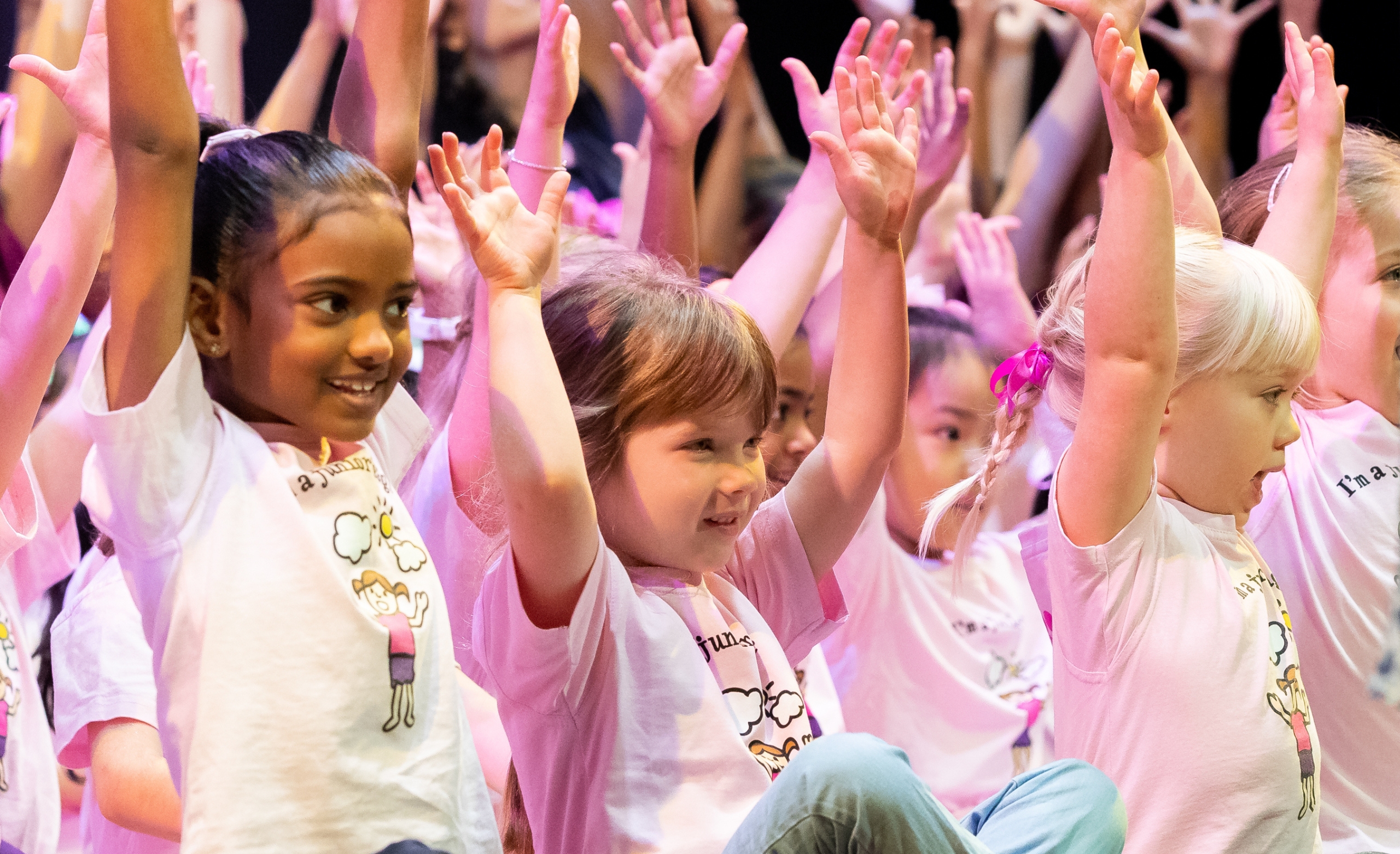 junior girls choir smiling with hands up