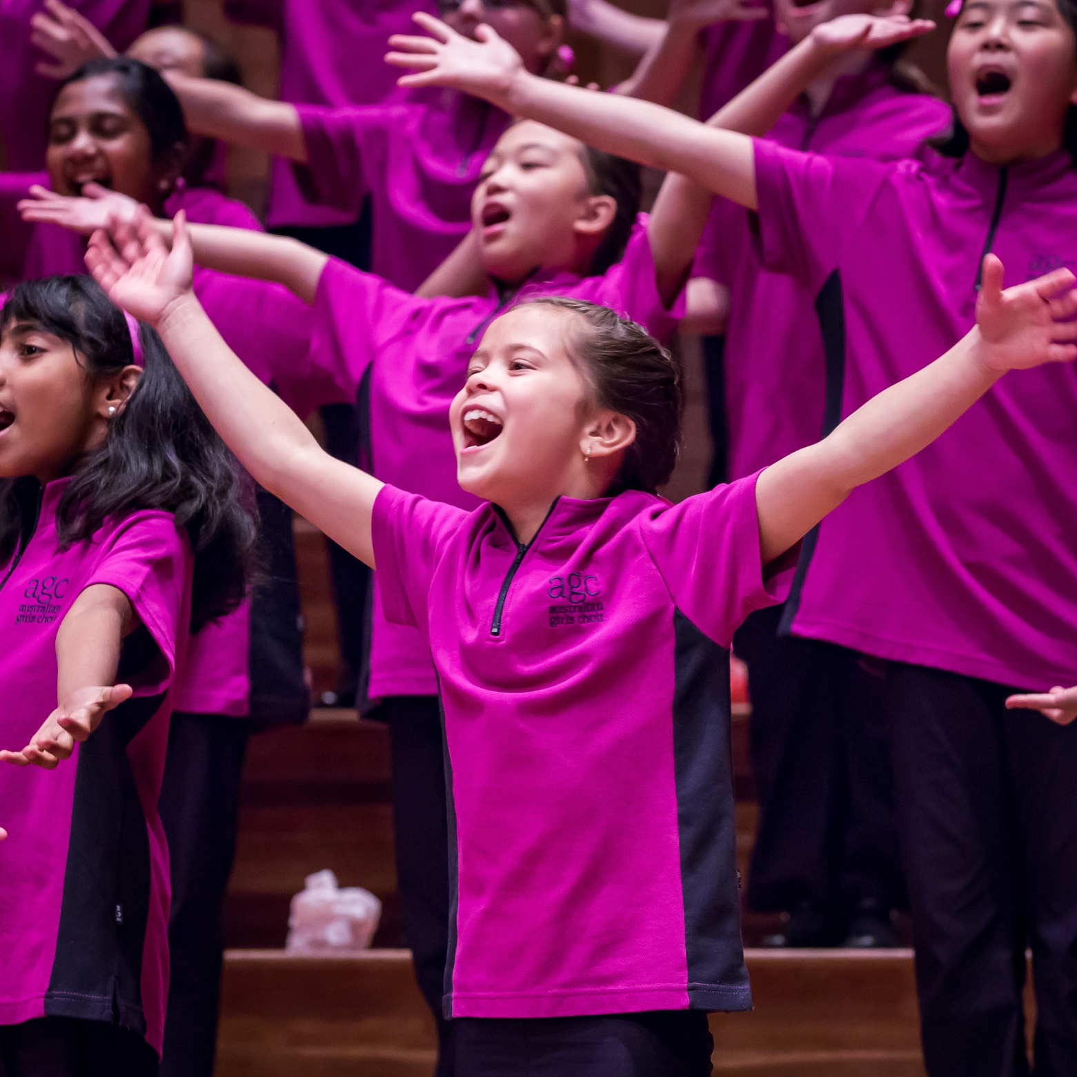 young chorister performing in pink uniform with arms spread