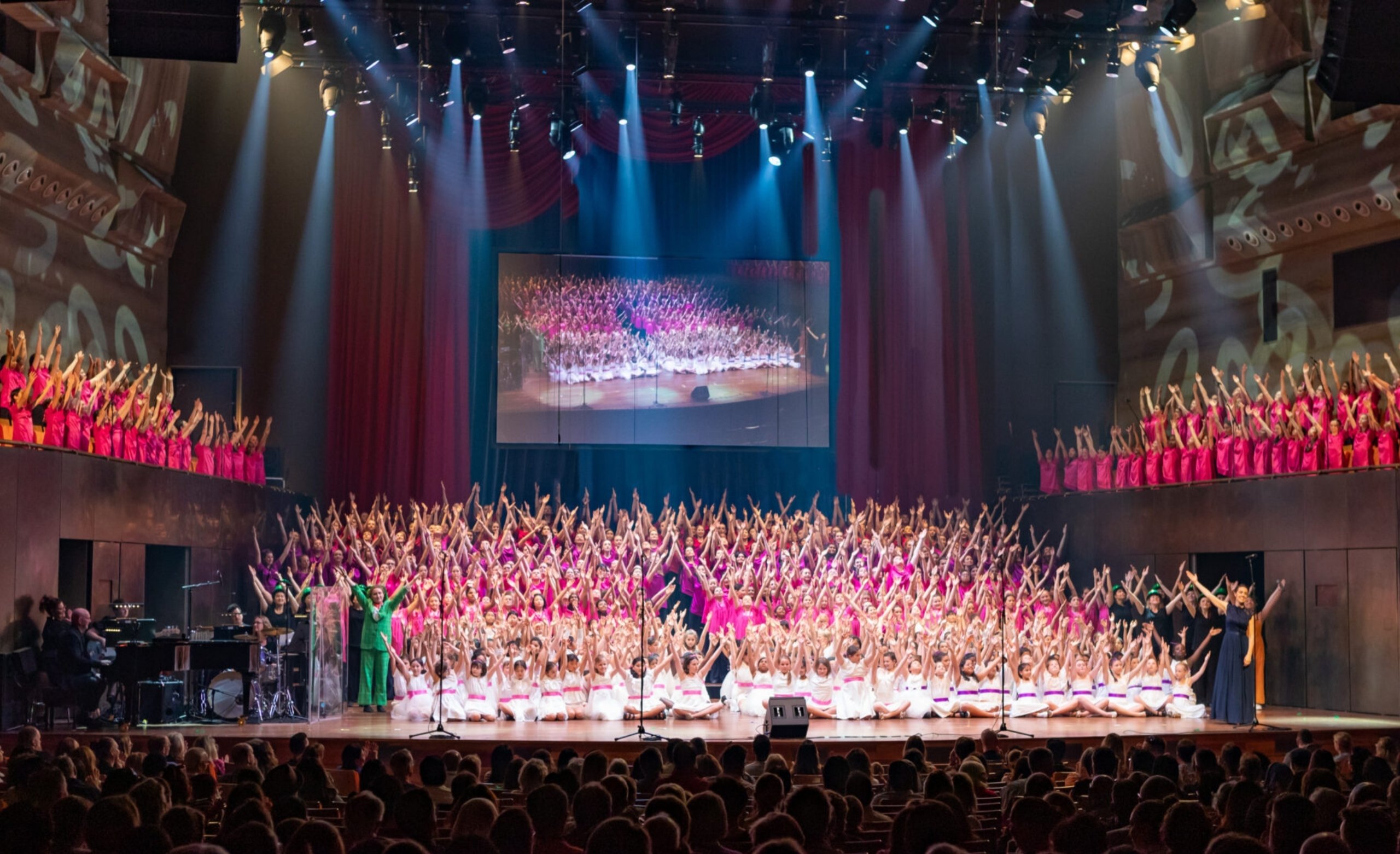 Choristers celebrate 40 years of the Australian Girls Choir together on stage during a concert.