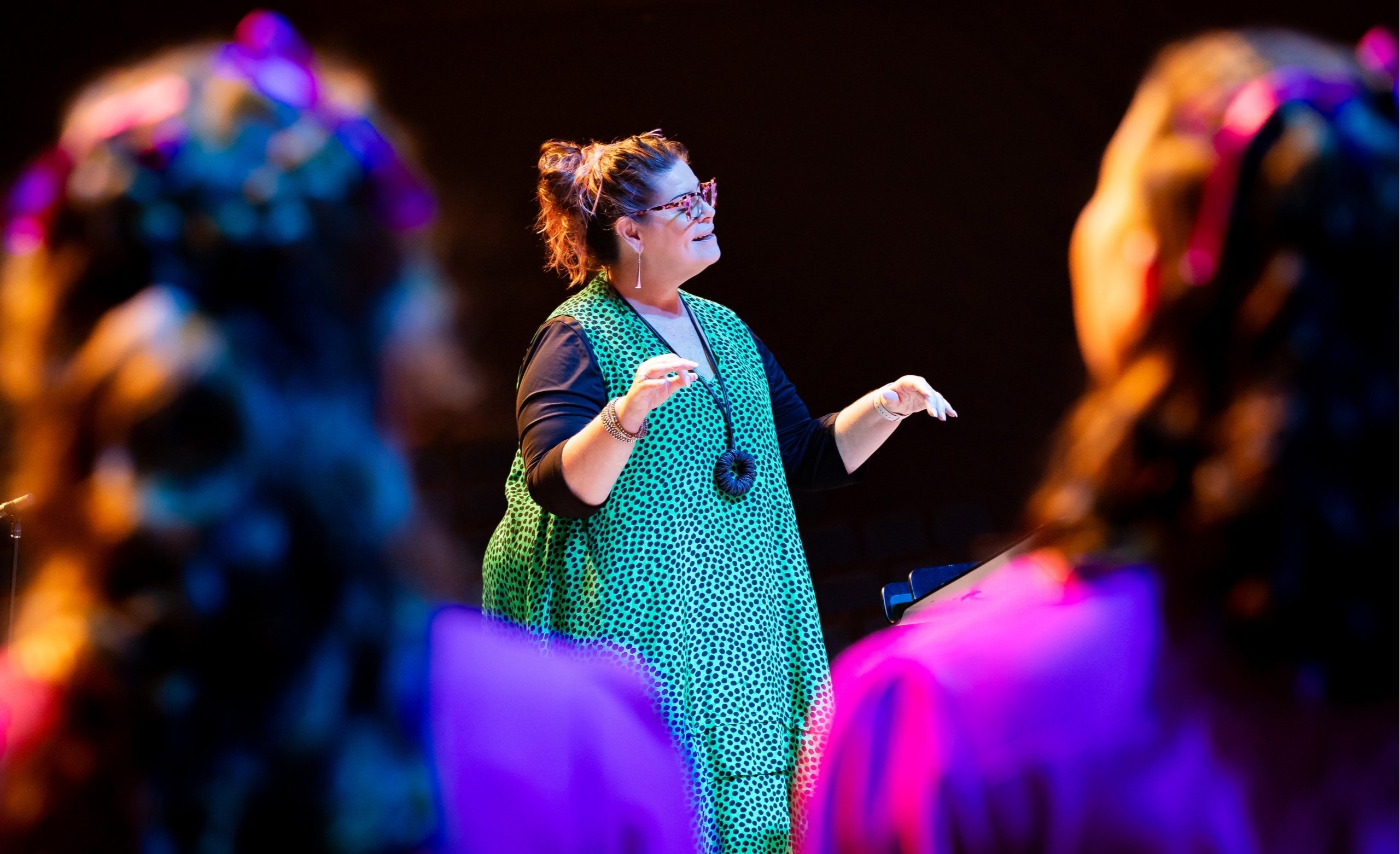 Our Artistic Director Vicki King conducts the Australian Girls Choir on stage during a concert.