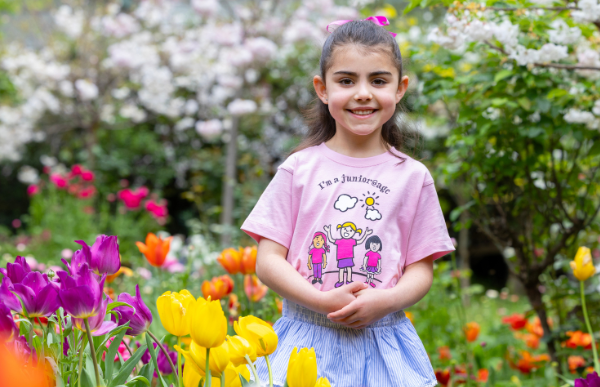 A junior@agc choristers stands in a beautiful flower garden