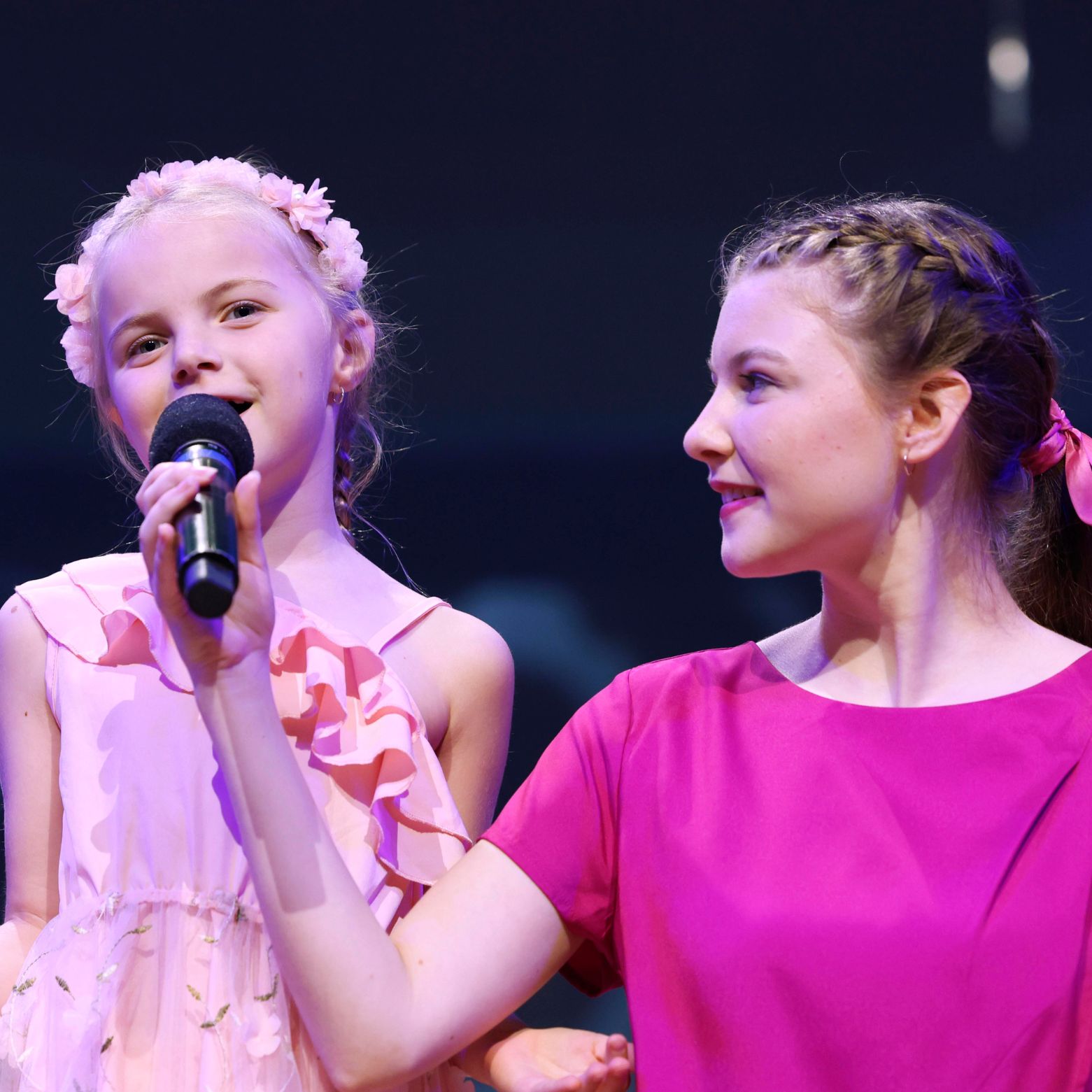 Performing Choir chorister holds the microphone up for a junior chorister at Annual Concert