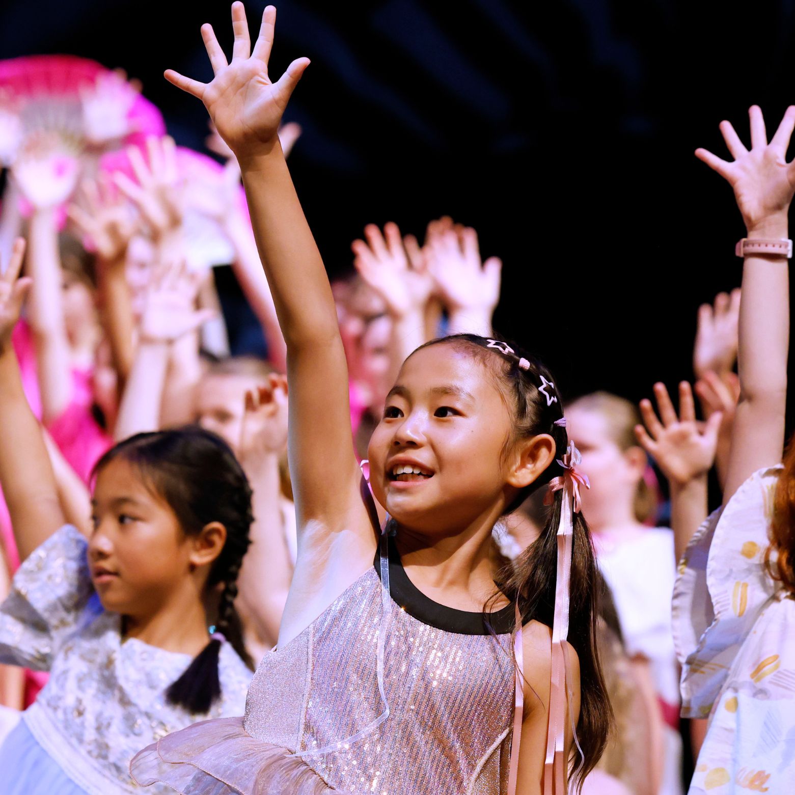 Junior@agc chorister reaches her arm up during a dance move